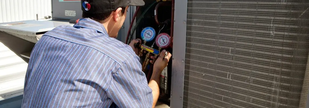 HVAC technician servicing a condenser unit in Zuni Pueblo