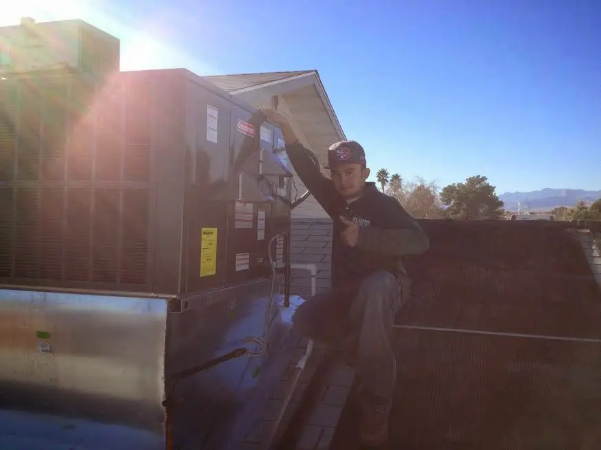 HVAC technician performing Air Duct Repair on a rooftop unit in Zuni Pueblo